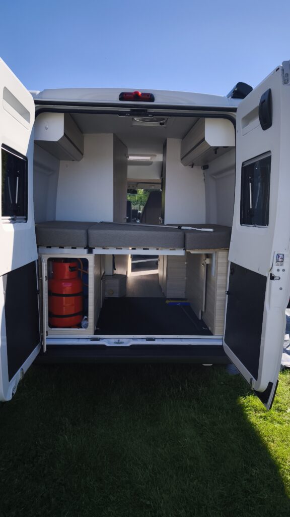 Obrázek interiéru obytného auta s pohodlnými sedacími plochami a úložným prostorem. Ideální pro kempování.