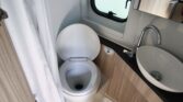 Obrázek interiéru karavanu s toaletou a umyvadlem. Moderní design a funkčnost pro pohodlné cestování.