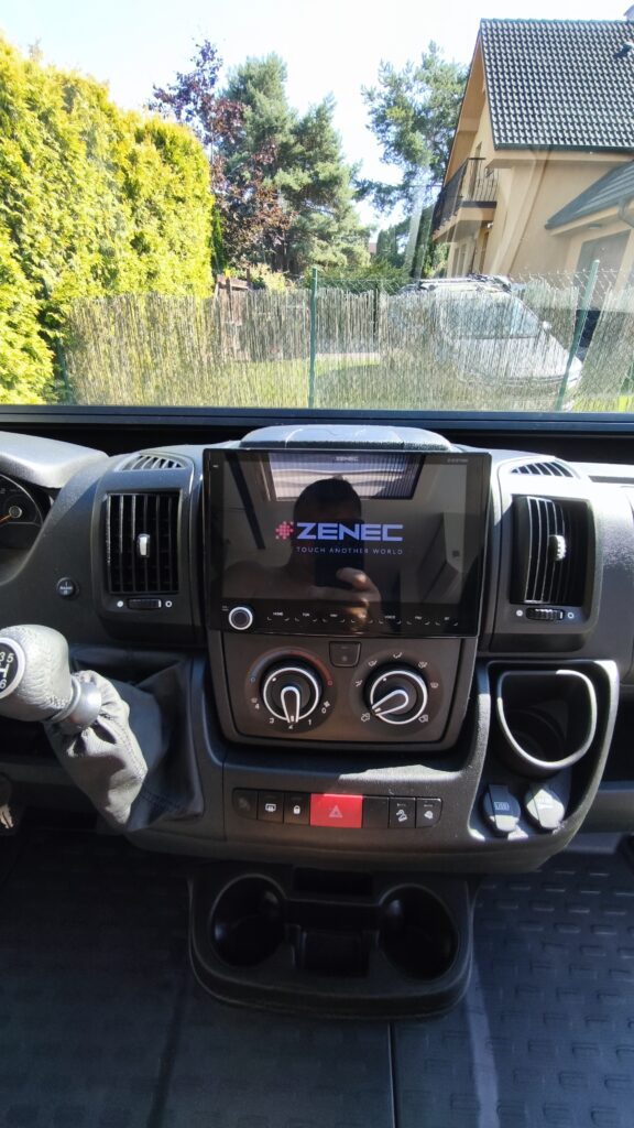 Zátiší interiéru obytného auta, moderní ovládací panel a příslušenství značky ZENEC. Komfortní vybavení na cesty.