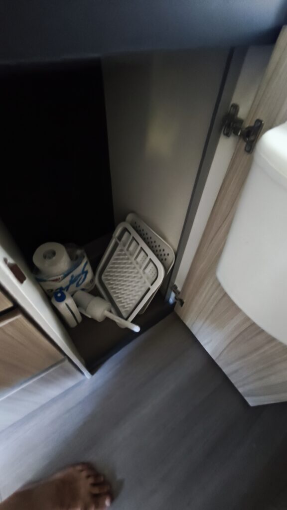 Obrázek interiéru karavanu, kde jsou vidět úložné prostory s úklidovými potřebami.