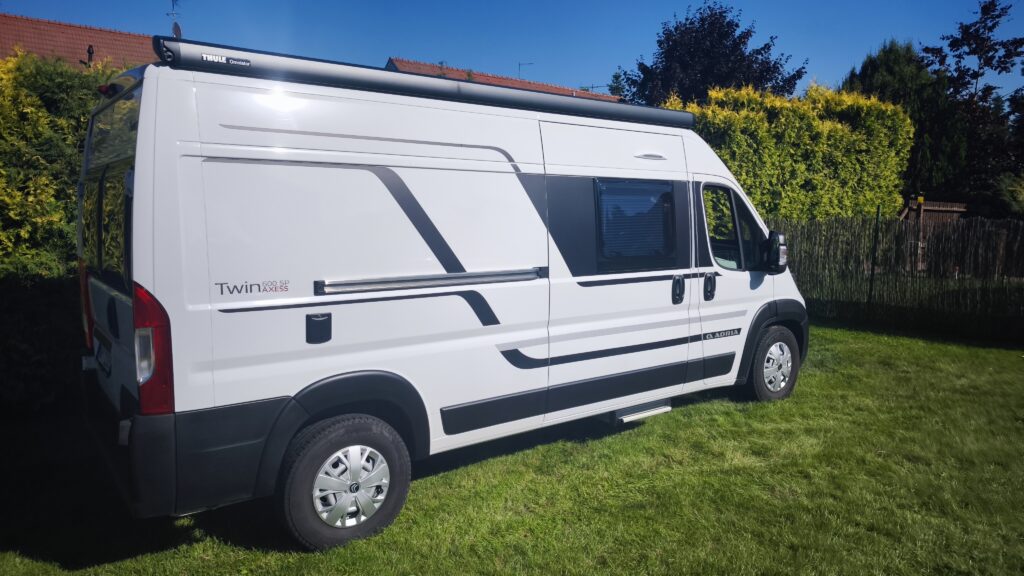 Obytné auto Adria Twin 600 SP AXESS na trávníku, ideální pro pohodlné cestování a kempování.