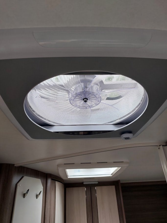 Obrázek interiéru karavanu s ventilátorem a střešním oknem. Moderní a pohodlné prostředí pro cestování.