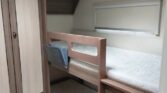 Obrázek ukazuje interiér karavanu s patrovými postelemi a úložným prostorem. Ideální pro rodinné výlety.