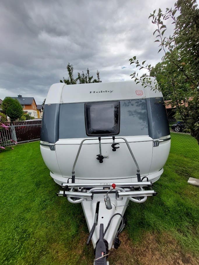 Karavan Hobby, moderní design s velkým oknem a přívěsem, ideální pro dobrodružné výlety.