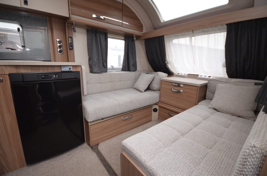 Obrázek interiéru karavanu s pohodlným sezením, kuchyňkou a moderním designem. Ideální pro cestování.