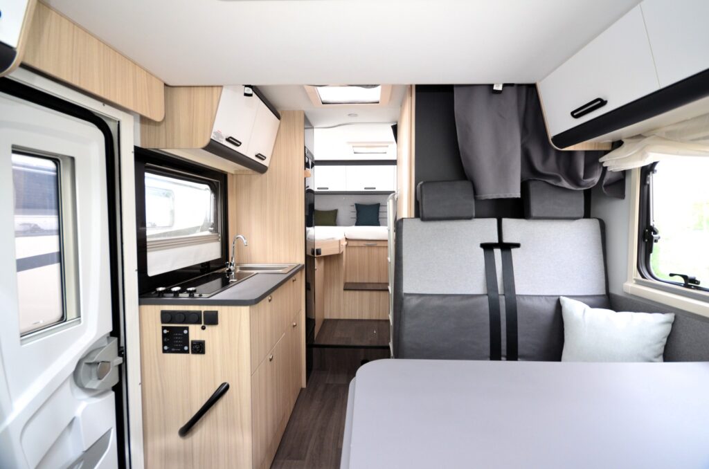Interiér obytného auta s moderním designem, kuchyň káva s úložným prostorem. Komfortní a prostorné.