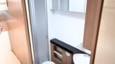 Interiér obytného vozu s koupelnou, vanou a úložným prostorem. Moderní a praktický design pro pohodlné cestování.