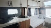 Interiér moderního karavanu s kuchyňkou, pohodlným sezením a úložným prostorem. Ideální pro cestování a rekreaci.