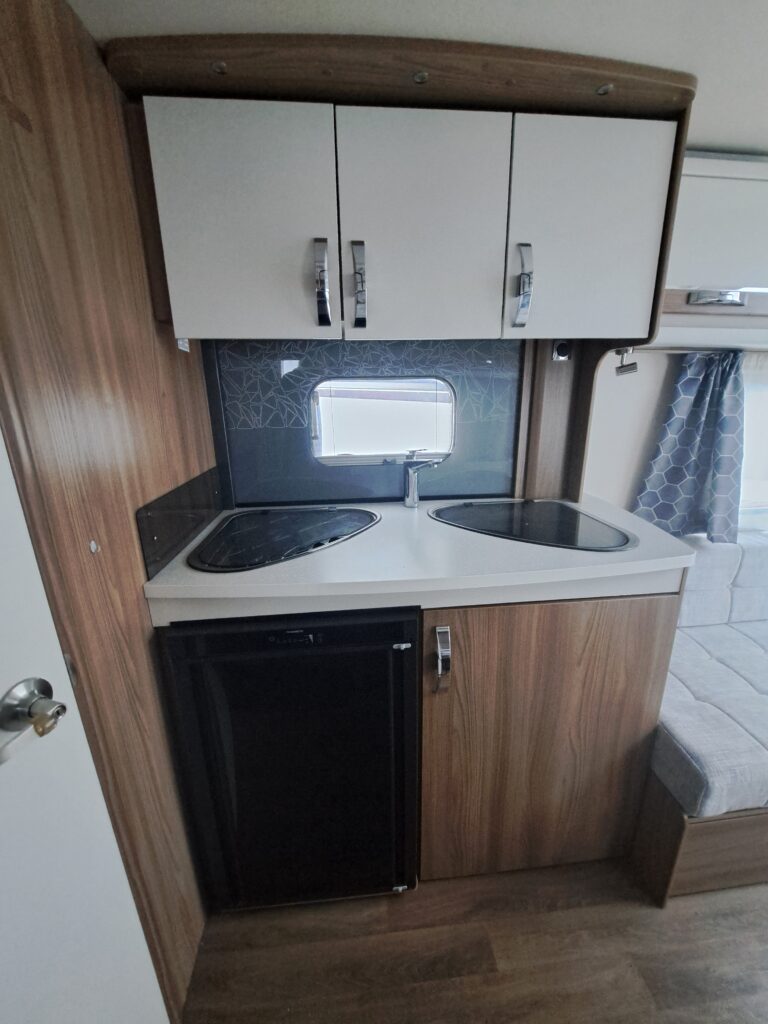 Kuchyňský kout v karavanu, moderní design s dřezem, lednicí a úložným prostorem. Ideální pro pohodové cestování.
