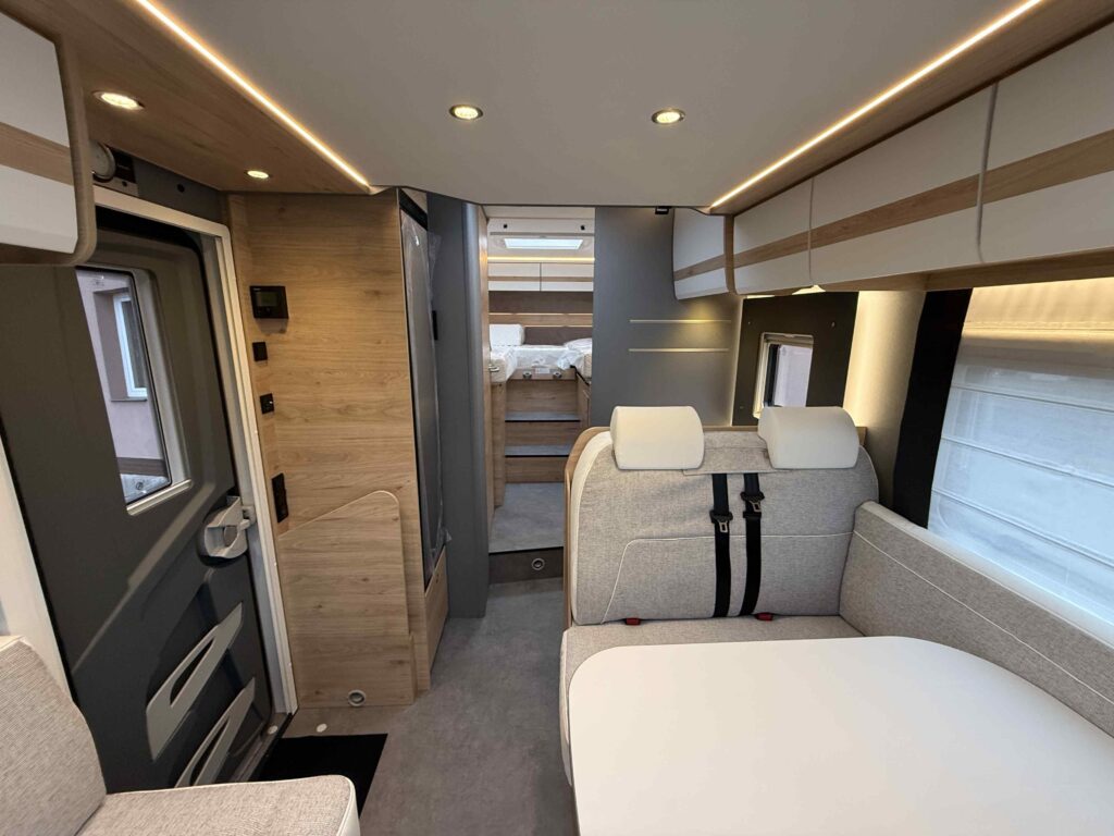 Obrázek interiéru moderního obytného auta s pohodlným uspořádáním a světlými prvky.