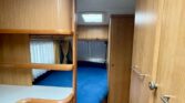 Interiér karavanu s dřevěnými prvky a modrou postelí, ideální pro pohodlné cestování.