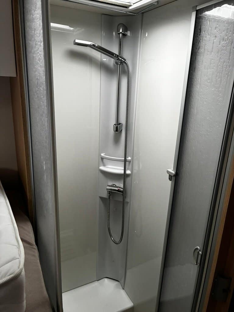Obrázek zobrazuje sprchový kout, ideální pro komfortní obytné auto. Udržuje rozměrný prostor.