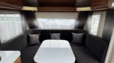 Interiér karavanu s pohodlným sezením a stolem, ideální pro relaxaci a společné chvíle.