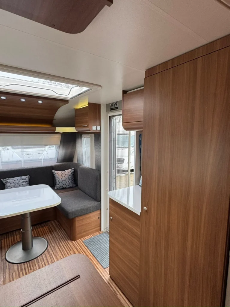 Moderní interiér karavanu s pohodlným sezením a kuchyňským koutem, ideální pro dobrodružné cestování.