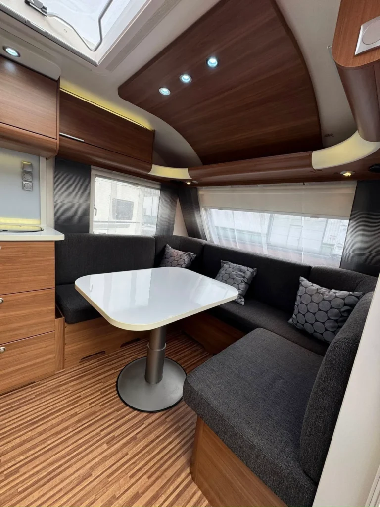 Interiér karavanu s moderním nábytkem a pohodlným sezením. Ideální pro cestování a relaxaci.