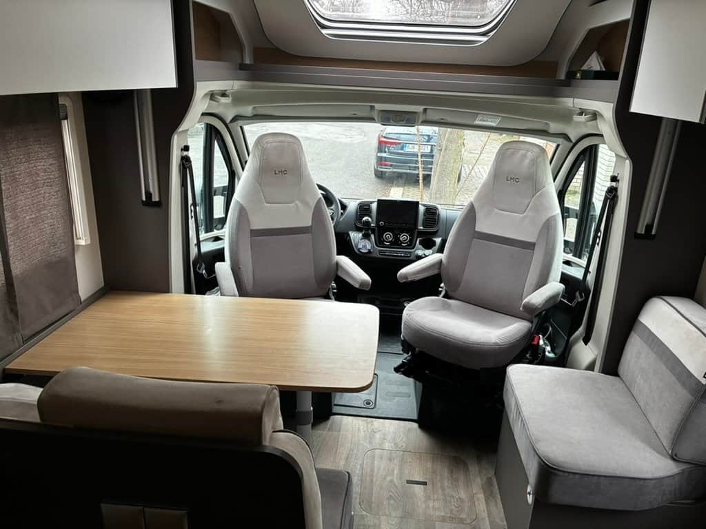 Interiér obytného auta LMC s pohodlnými sedadly a stolem pro odpočinek. Ideální pro cestování a relaxaci.