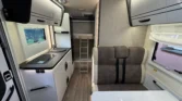 Obrázek interiéru moderního obytného auta s kuchyní a pohodlným sezením.