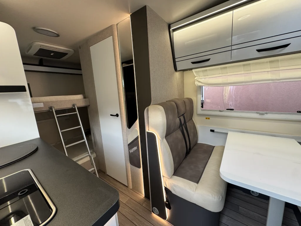 Moderní interiér karavanu se sedací soupravou a kuchyňským koutem. Všestranné využití pro cestování a odpočinek.