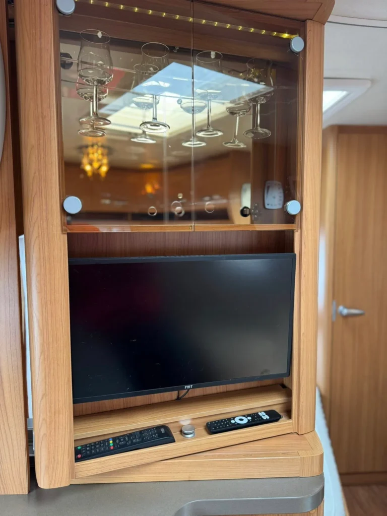 Moderní interiér obytného vozu s televizí a sklenicemi. Komfortní a praktický prostor pro cestování.