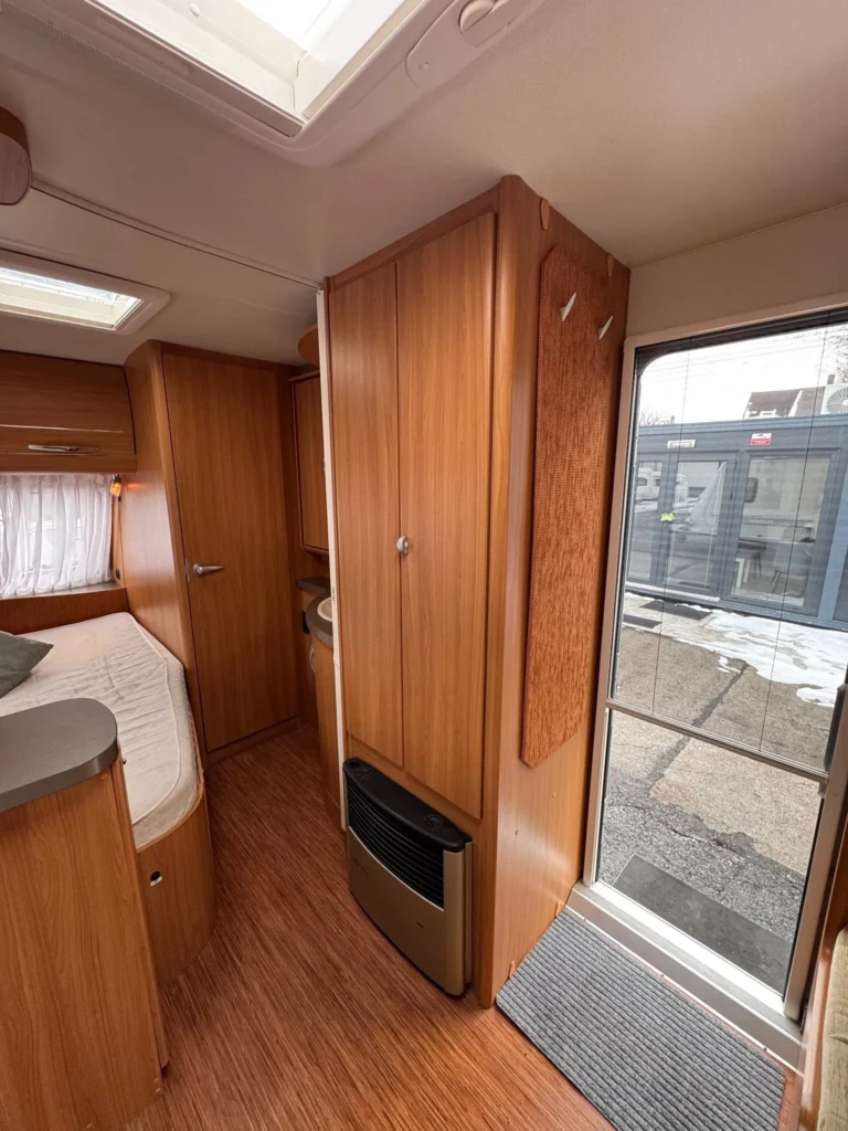 Interiér karavanu s dřevěnými prvky a pohodlným uspořádáním. Ideální pro rodinné výlety.