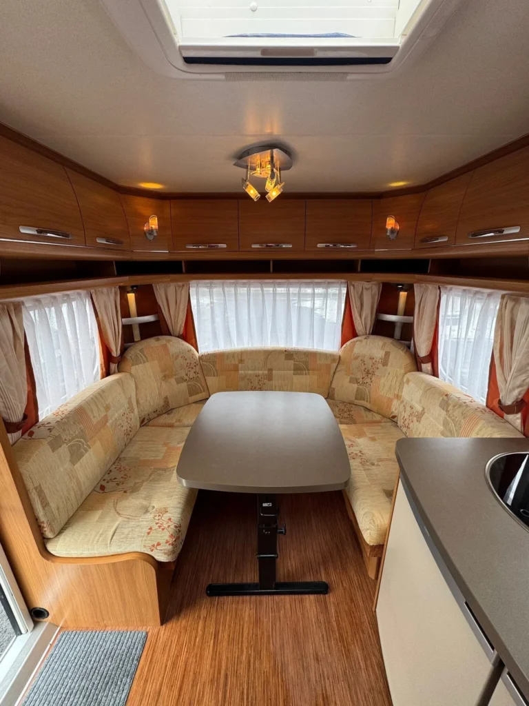 Prostorný interiér karavanu s pohodlným sezením a stolem. Ideální pro rodinné výlety.