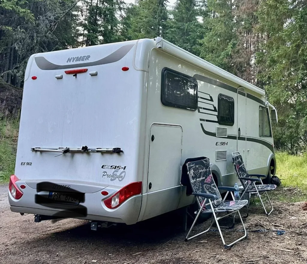 Obytné auto Hymer Exsis-I, ideální pro kempování v přírodě se dvěma židlemi vedle.