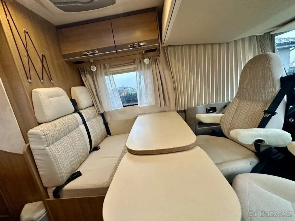 Interiér obytného auta s pohodlným sezením a stolem. Moderní design pro komfortní cestování.