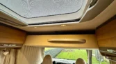 Interiér obytného auta s moderním designem, stropním oknem a pohodlnými sedačkami. Ideální pro cestování.