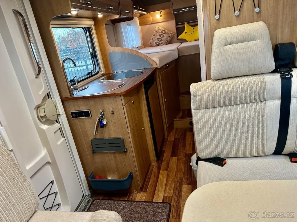 Interiér obytného auta s kuchyňským koutem a pohodlným sezením. Ideální pro cestování a odpočinek.