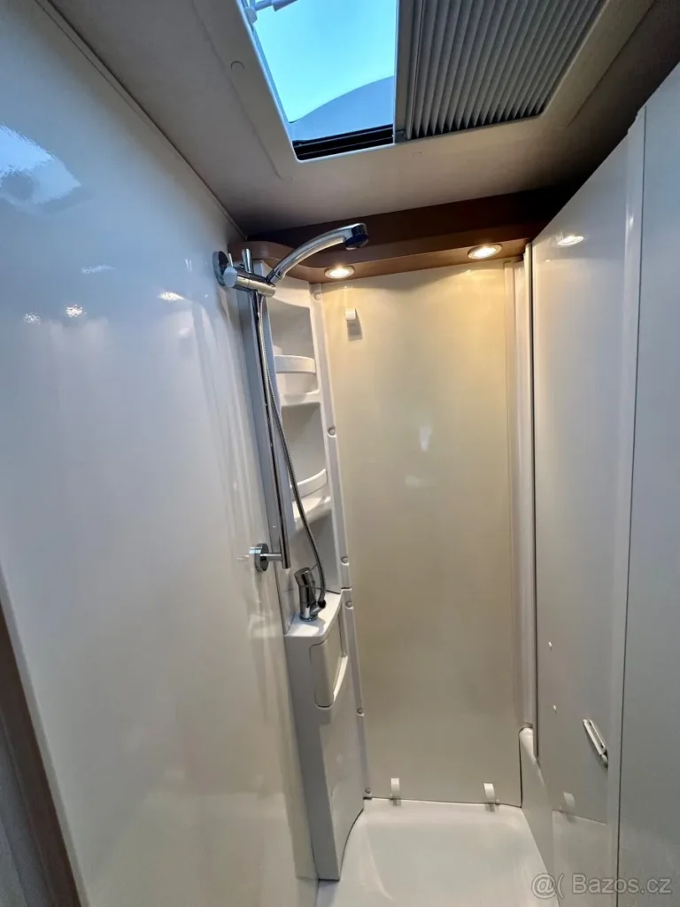 Obrázek zobrazuje moderní sprchový kout v obytném voze. Vhodný pro pohodlné kempování.