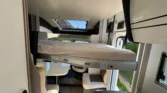 Interiér moderního obytného auta s rozkládací postelí a stylovým posezením.