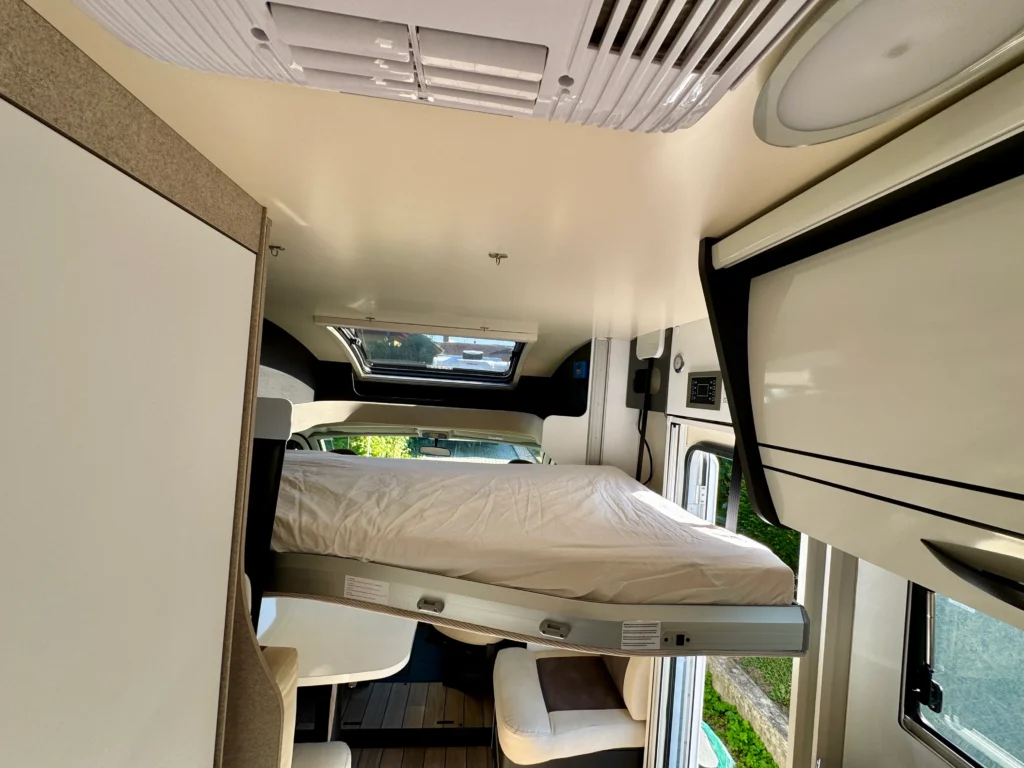 Interiér obytného auta s rozkládacím lůžkem a moderním designem. Ideální pro pohodlné cestování.