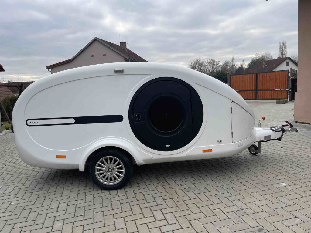 Moderní karavan AYAZ s aerodynamickým designem vhodný pro pohodlné cestování a kempování.