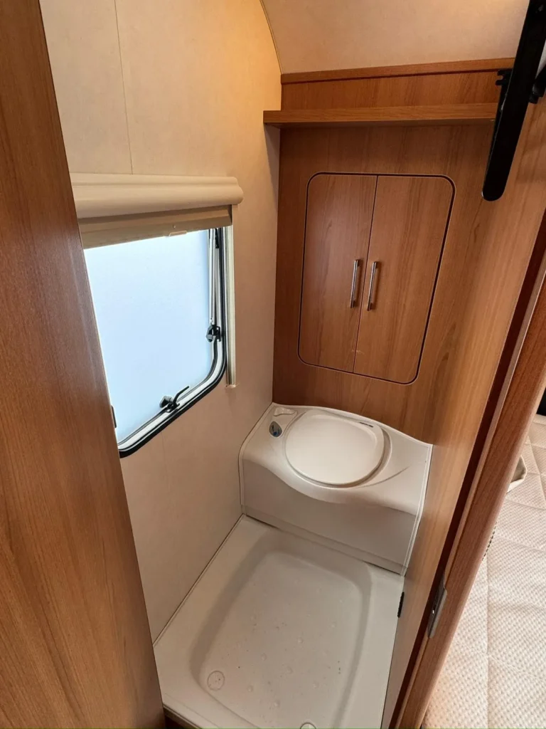 Koupelna v karavanu s dřezem a skříňkami, ideální pro pohodlné cestování.