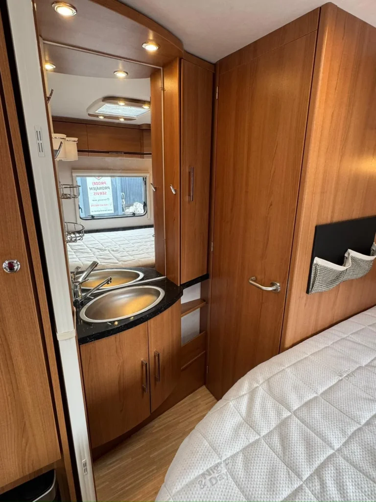 Moderní interiér obytného auta s kuchyňským koutem a ložnou částí. Ideální pro pohodlné cestování a kempování.