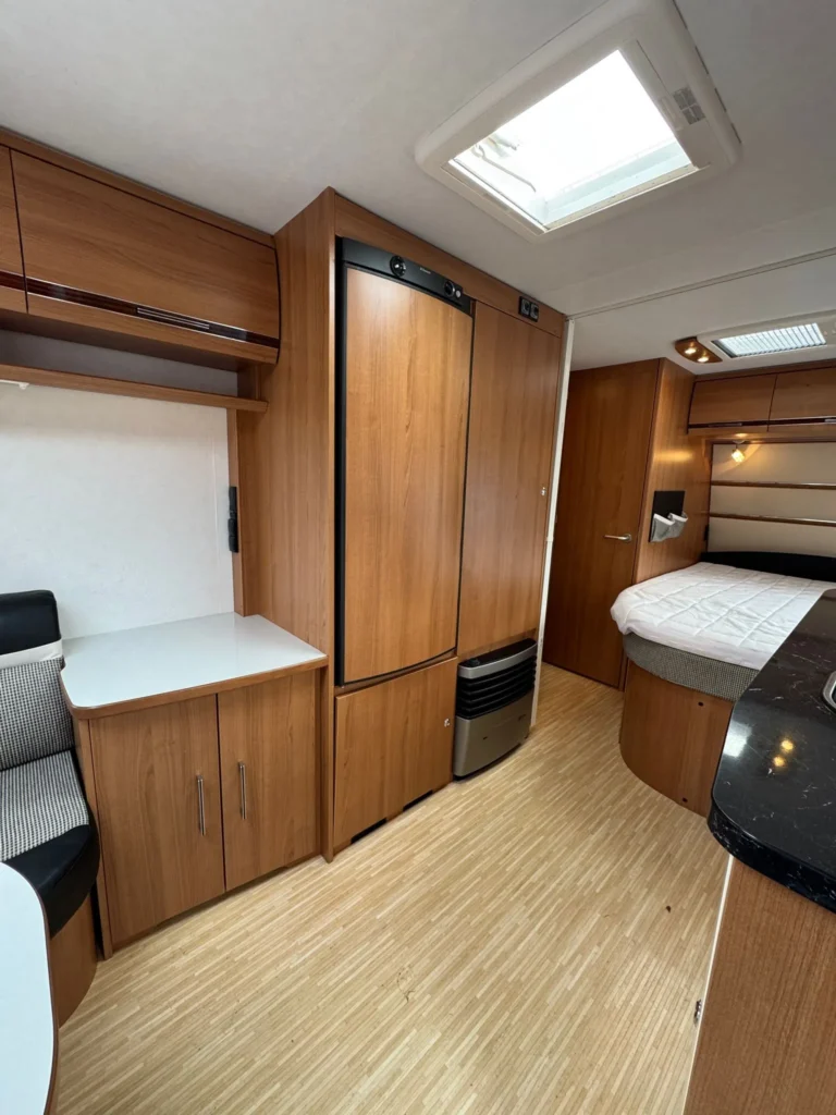 Interiér karavanu s dřevěnými prvky, pohodlným sezením a moderním vybavením. Ideální pro dobrodružství.