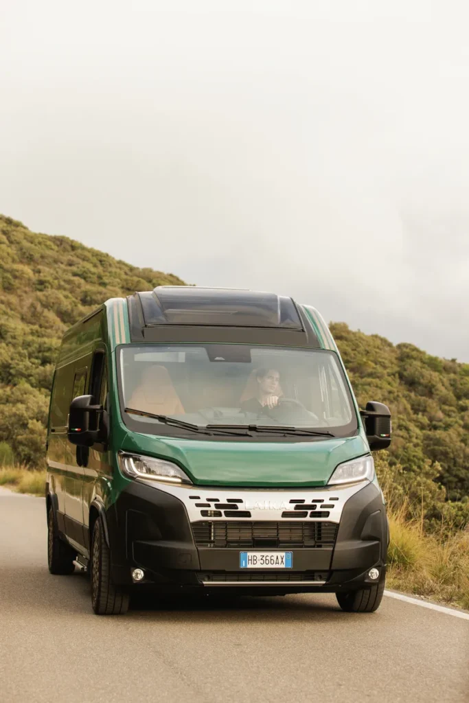 Obytné auto Laika na silnici, ideální pro dobrodružství a cestování. Přírodní scenérie v pozadí dodává kouzlo.