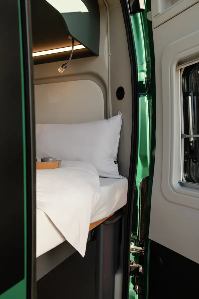 Interiér obytného auta s pohodlnou postelí a moderním osvětlením. Ideální na cesty!