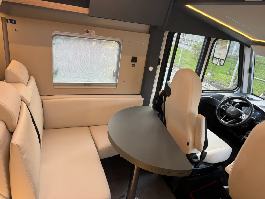 Interiér obytného auta Fiat s pohodlným sezením a stůl, ideální pro společné chvíle. Moderní a prostorné uspořádání.
