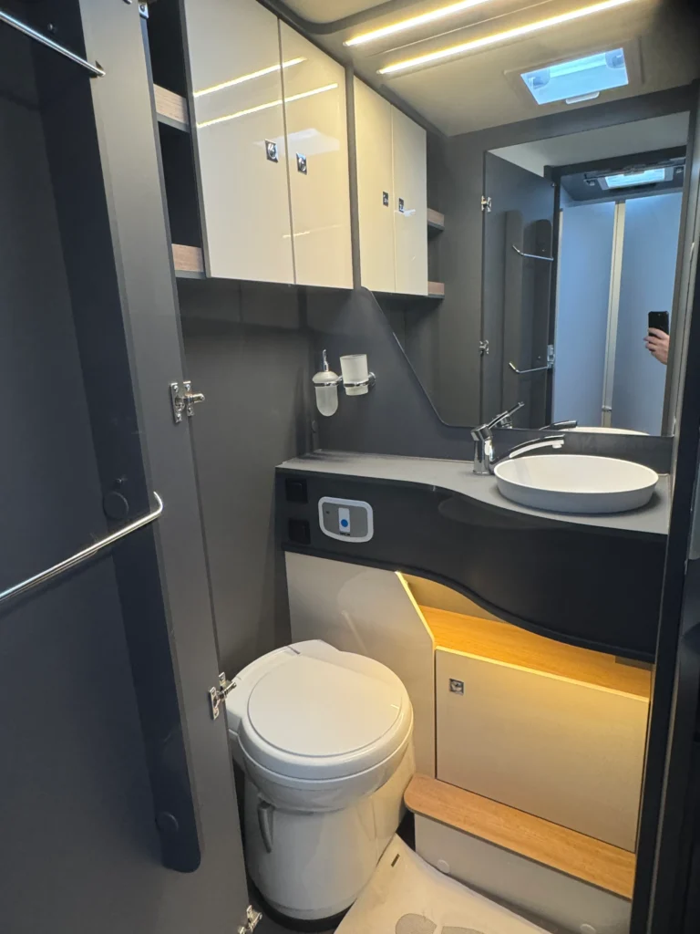 Luxusní interiér karavanu s moderním umyvadlem a toaletou. Ideální pro pohodlné cestování.