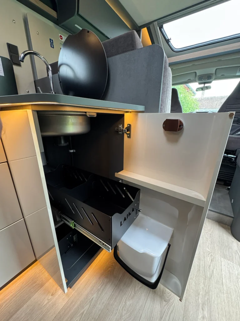 Interiér karavanu Laika s dřezem, úložným prostorem a toaletou. Moderní design a funkčnost.