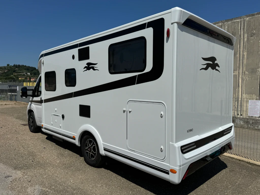 Bílý obytný přívěs s černými detaily, značky s výrazem. Zajímavý design pro kempování a cestování.