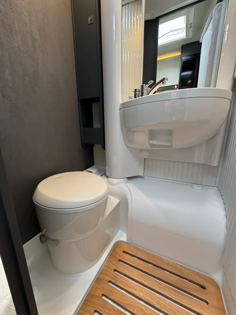 Interiér koupelny obytného vozu se sprchovým koutem a moderním umyvadlem. Elegantní design a funkčnost.