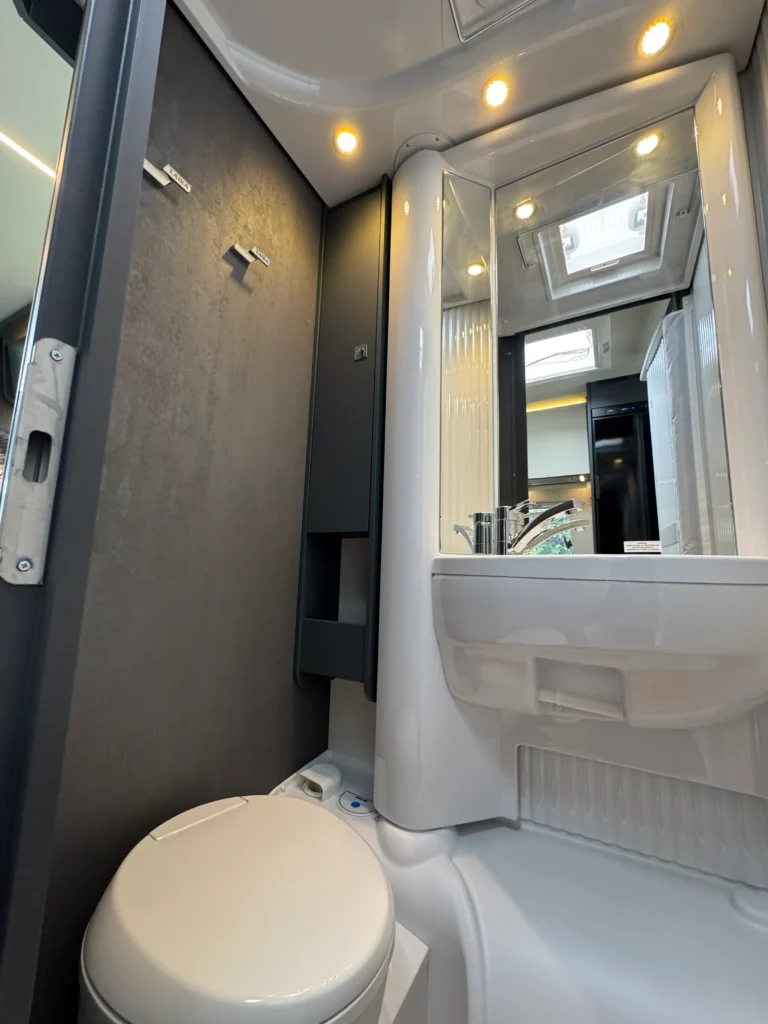 Koupelna v obytném autě, moderní design s umyvadlem a sprchou. Vhodné pro pohodlné cestování.