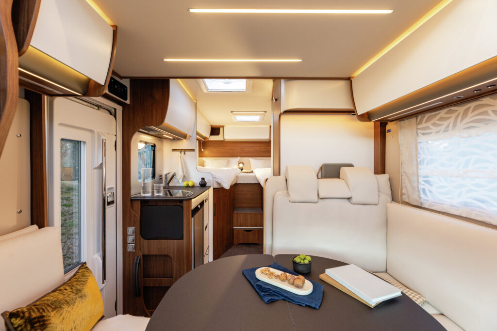 Obrázek interiéru moderního obytného auta s pohodlným posezením a plně vybavenou kuchyní.
