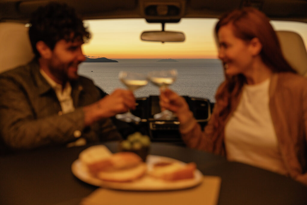 Obytné auto s krásným výhledem na moře, dvojice si užívá nezapomenutelný okamžik.