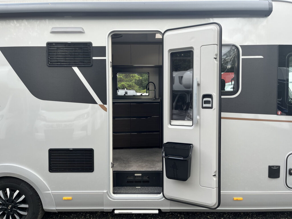 Obytné auto s otevřenými dveřmi, moderní design a prostorný interiér. Značka a model nejsou viditelné.