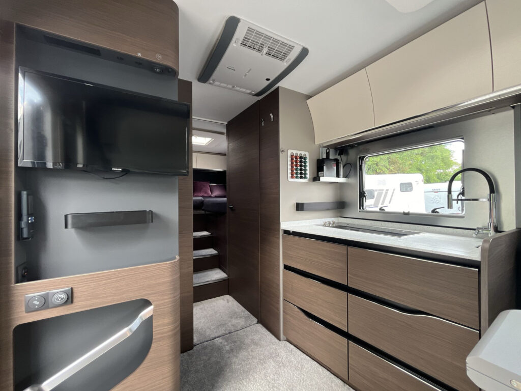 Interiér moderního obytného auta s kuchyňským koutem a pohodlnými úložnými prostory. Ideální pro cestování.