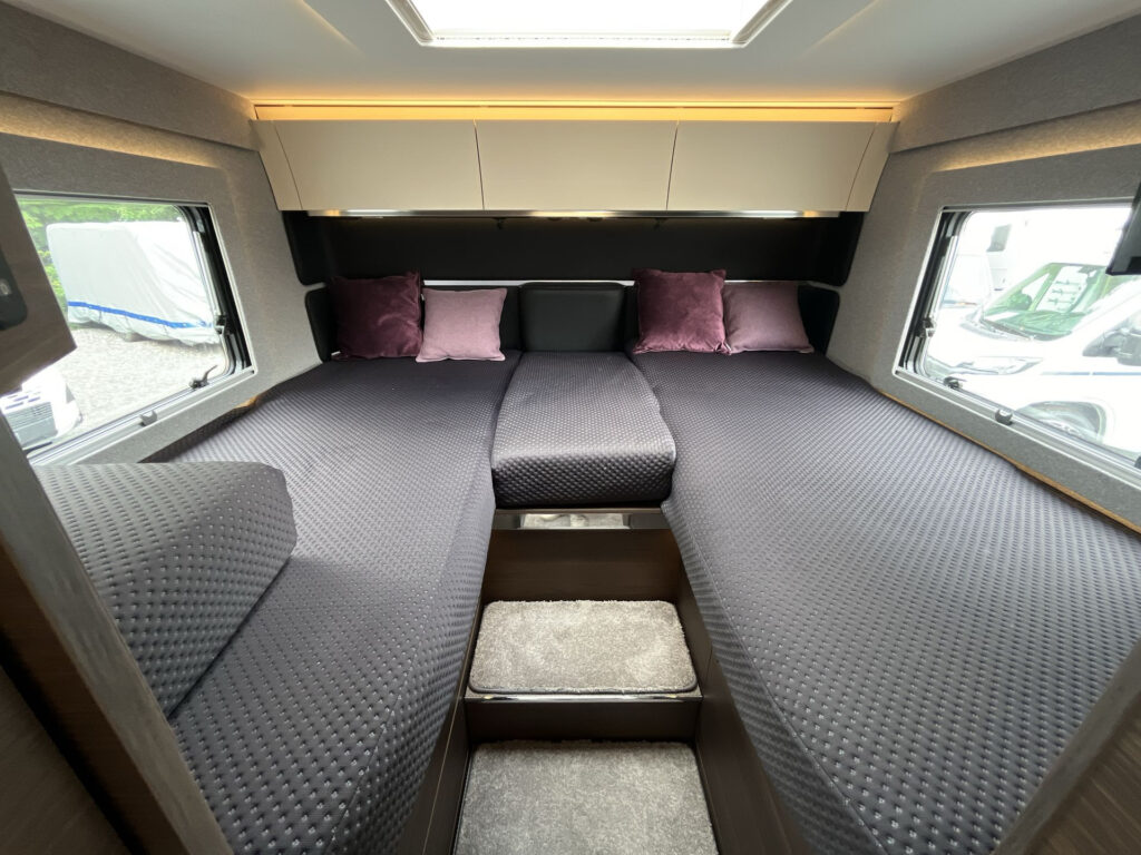 Interiér obytného vozu s pohodlnými lůžky, příjemnými polštáři a moderním designem. Skvělé pro relaxaci na cestách.