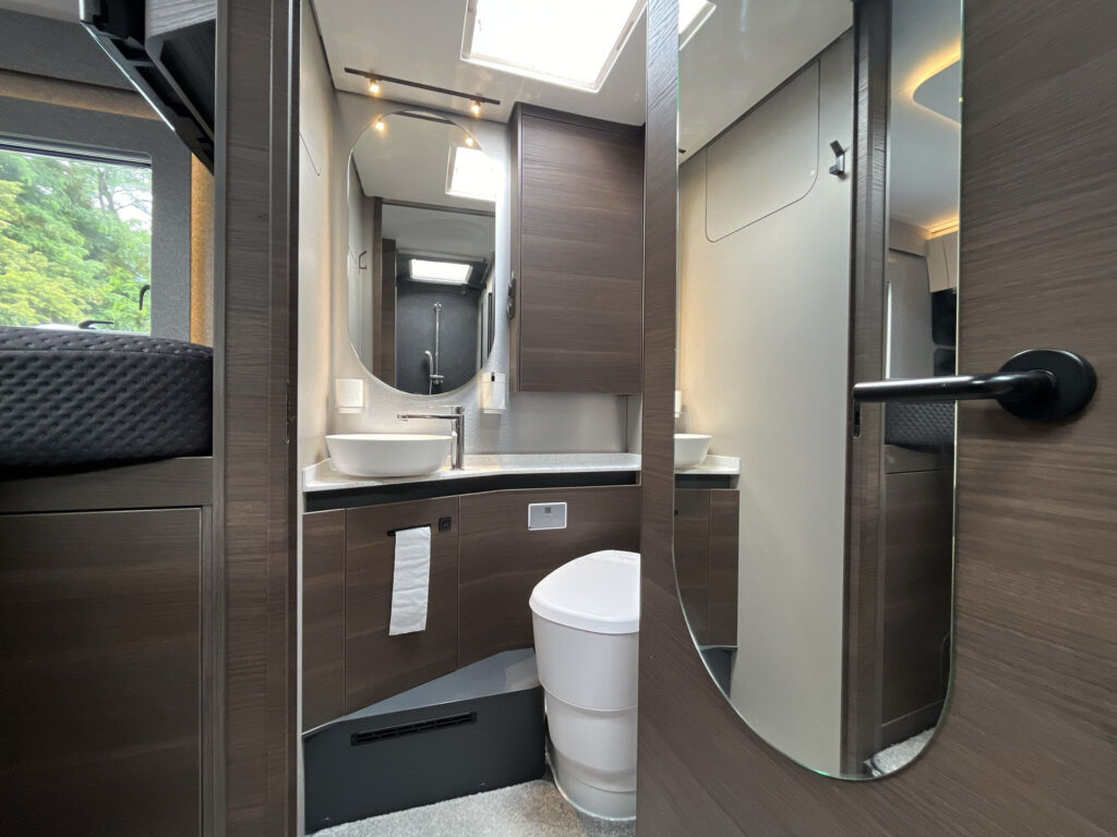 Obrázek interiéru obytného auta s moderní koupelnou. Elegantní design a funkčnost pro cestování.